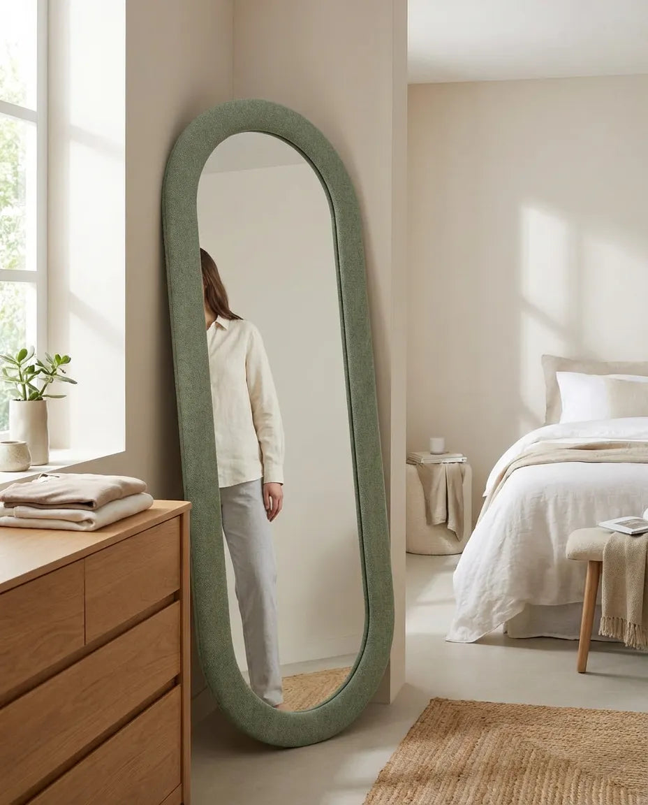 Person standing in front of a large green  fabric mirror in a bedroom.